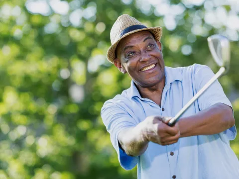 Mature golfer teeing off