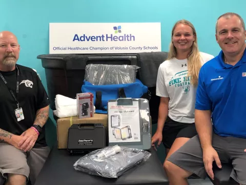 Two man and a woman sitting around heat illness Supplies. 