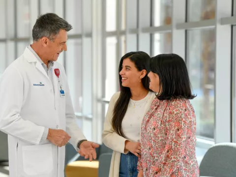 Male physician speaking with two female patients