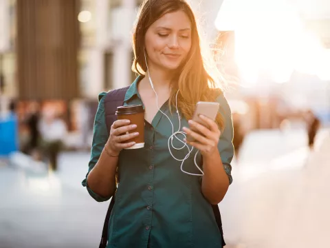 Woman drinking coffee in the morning while looking at her phone.