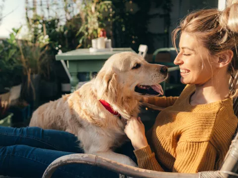 Woman sitting in a chair while on a porch with her dog.