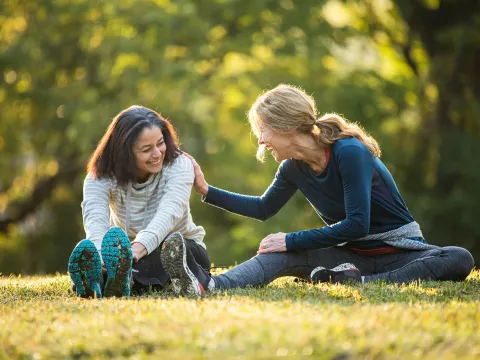 Two friends stretching in the in park. 
