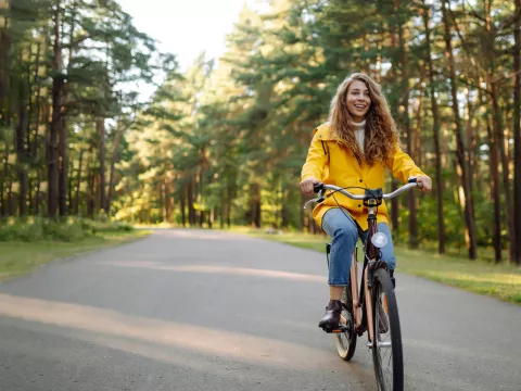 Woman riding on a bicycle in a forested area.