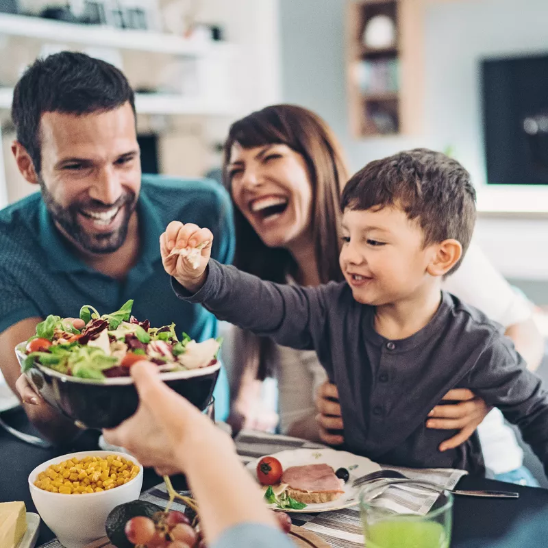 A Family Gathers Around The Kitchen Table To Enjoy Some Healthy Foods.