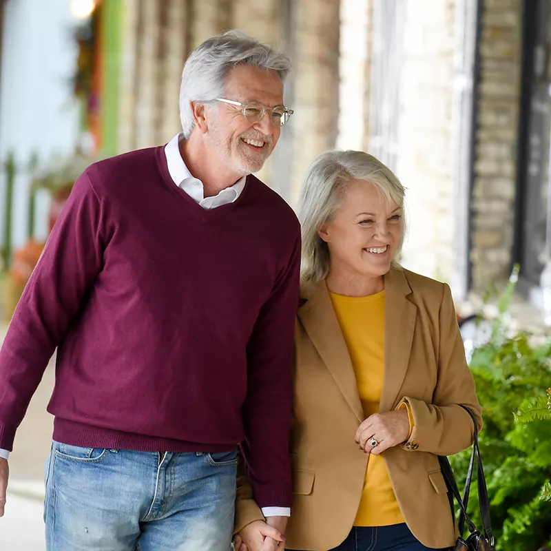 Elderly couple walking down a sidewalk window shopping.