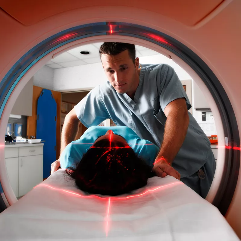 CT tech assisting patient while she gets a scan