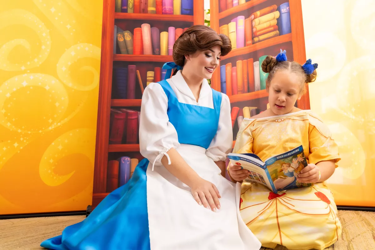 Disney Princess Belle reads with a young patient at AdventHealth for Children in Orlando.
