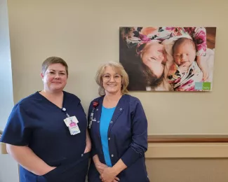 Lactation consultants stand in front of a mom with her newborn
