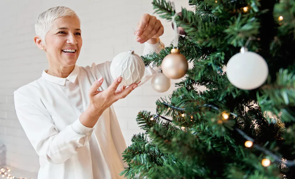 Woman hangs ornament in memory of loved one.