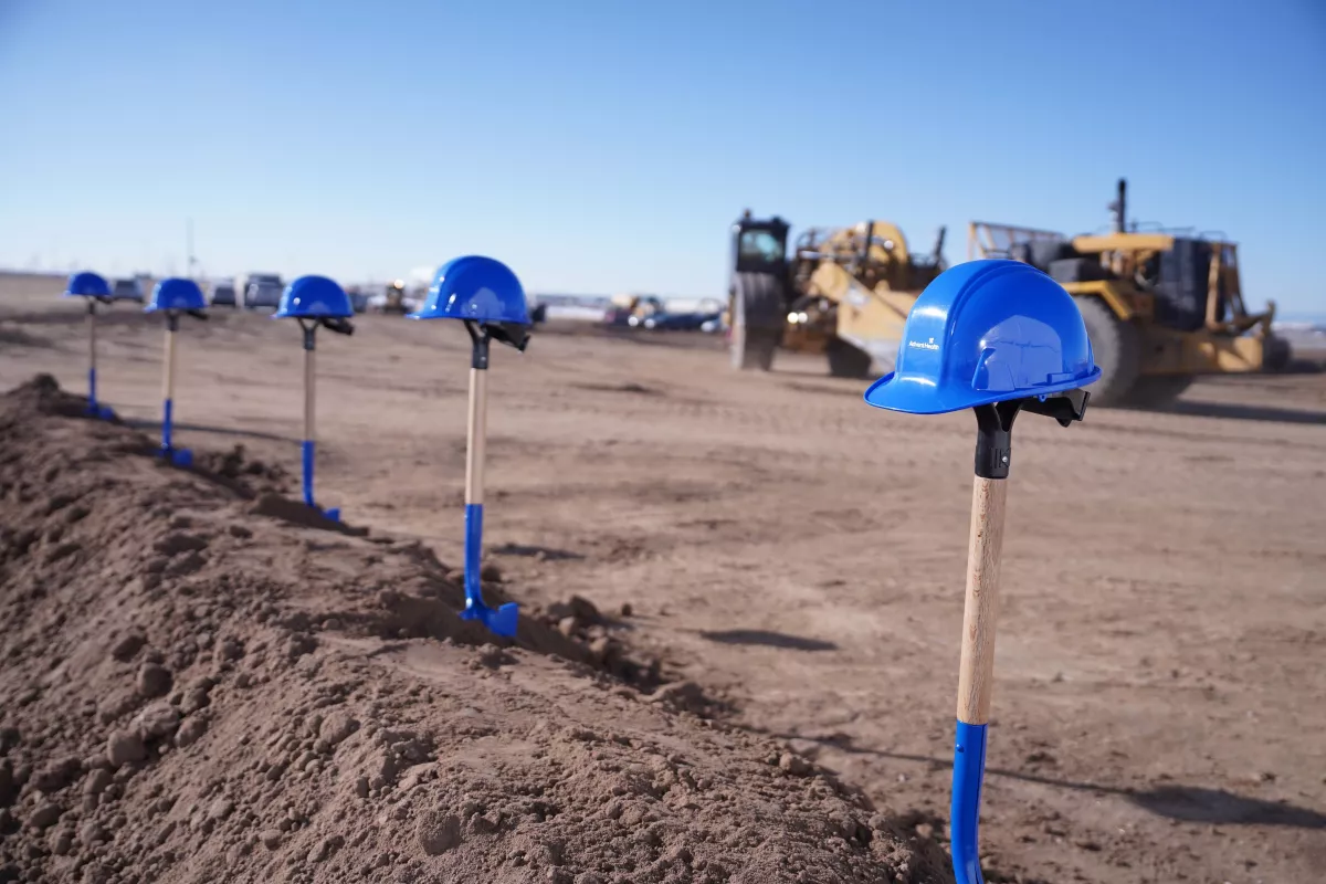 Shovels and hard hats sit in dirt at a construction site