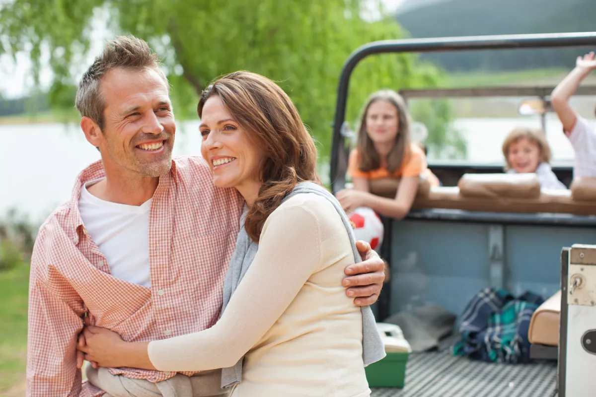 Man hugs wife with kids in the background
