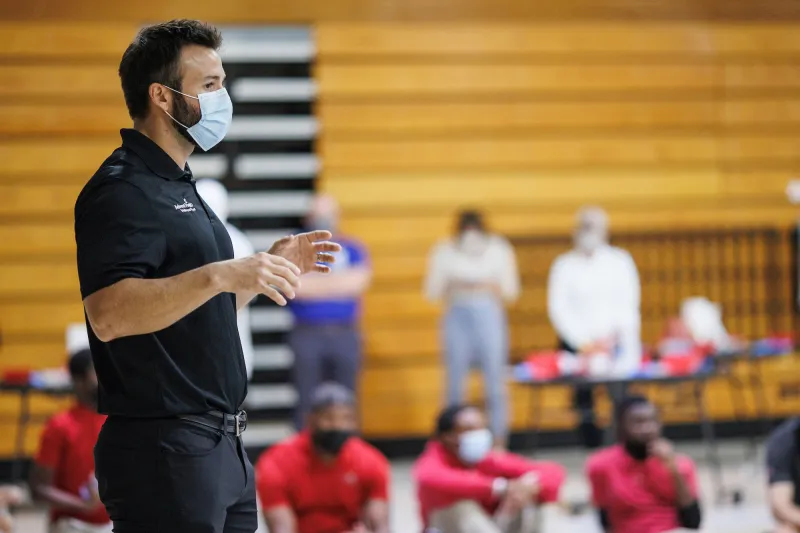 A masked man on stage giving a presentation