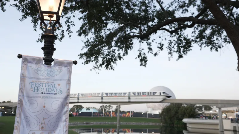 Epcot International Festival of the Holidays banner with monorail and Spaceship Earth in the background.