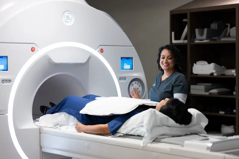 A imaging technician talking with a patient about to get a MRI.